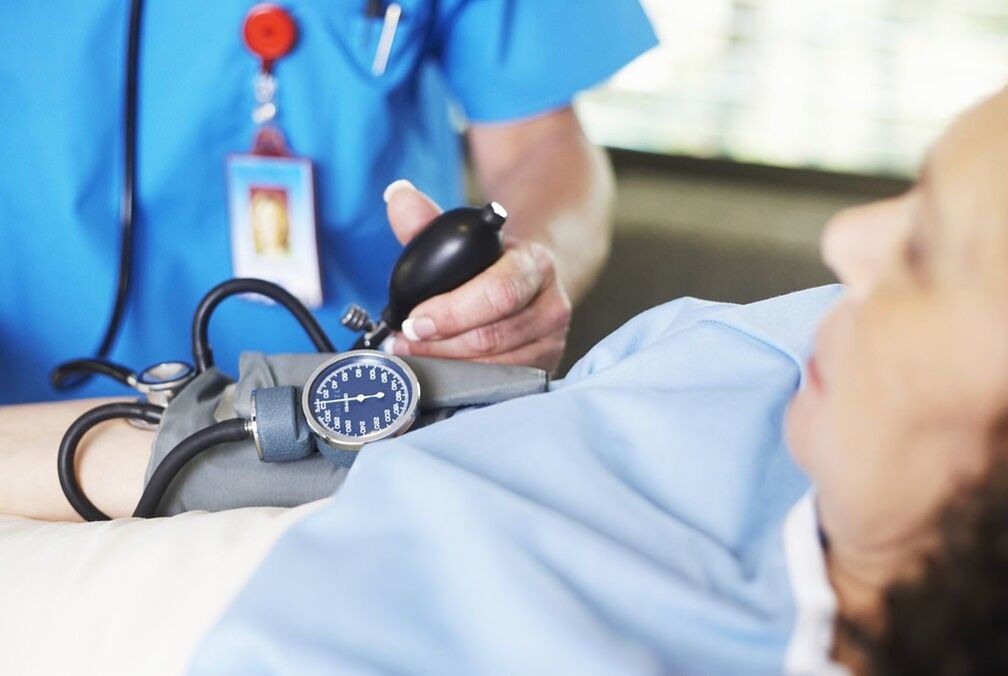 Gydytojas matuoja hipertenzijos sergančio paciento slėgį